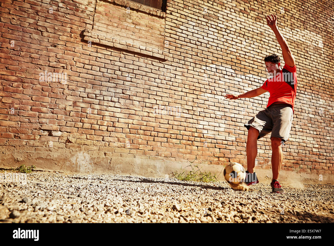 Young man playing soccer on wasteland Stock Photo