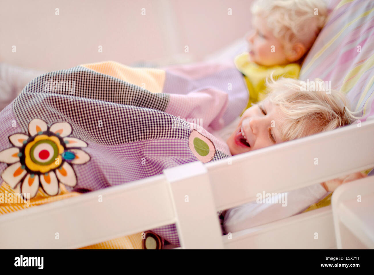 Two young brothers lying in bed, one laughing Stock Photo
