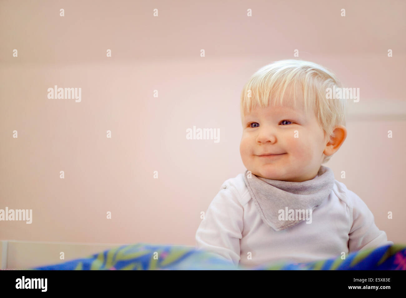 Portrait of cute fourteen month old baby boy sitting on duvet Stock Photo