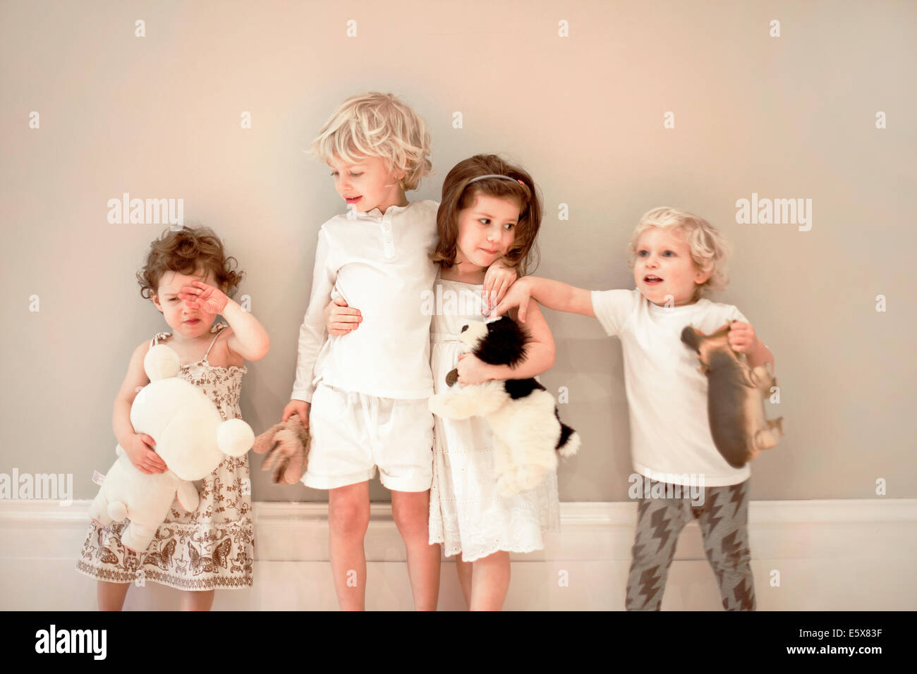 Portrait of four young children in a row, one crying Stock Photo