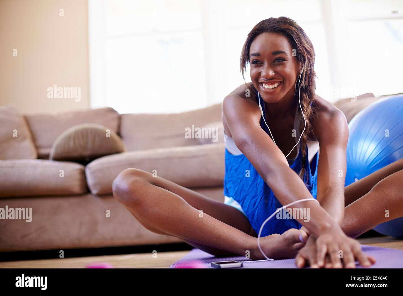 Young woman exercising and stretching on sitting room floor Stock Photo