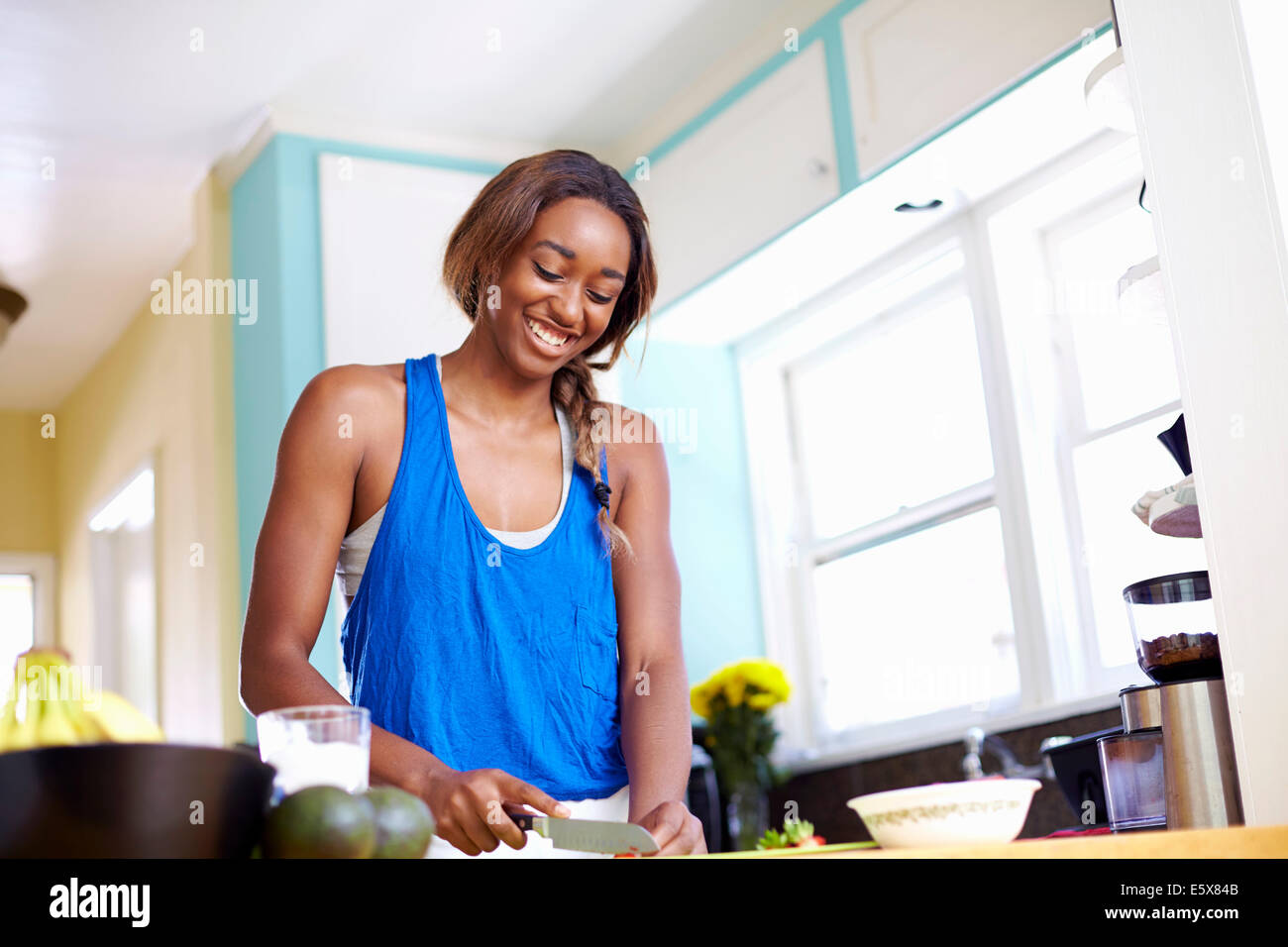 Young woman taking a training break, preparing food in kitchen Stock Photo