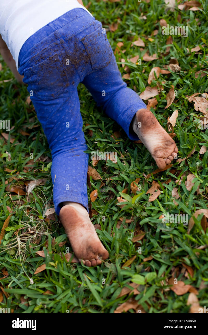 Four year old girl waist down crawling on garden grass Stock Photo