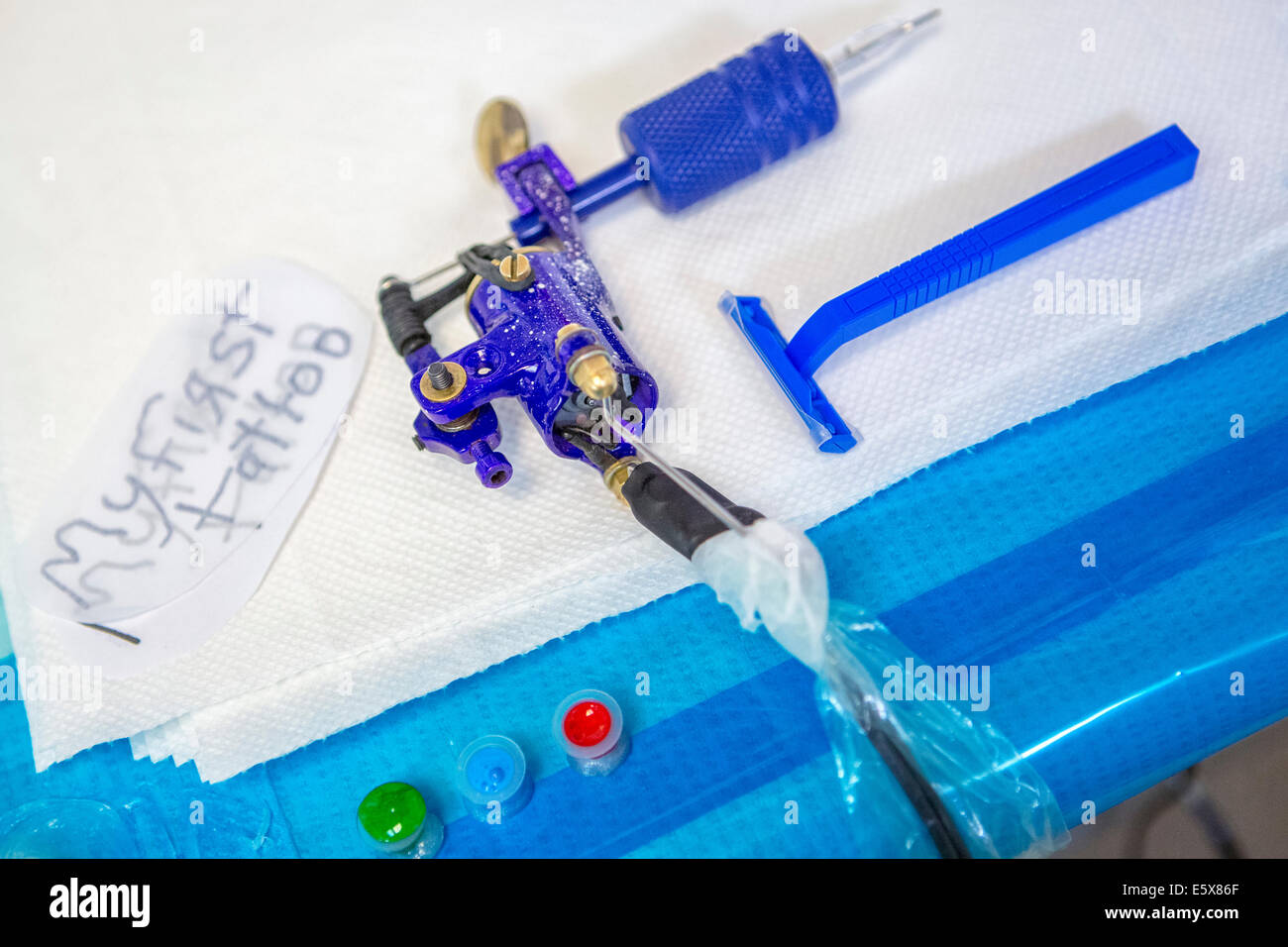 Close up of tattoo gun, razor, ink and "my first tattoo" design on