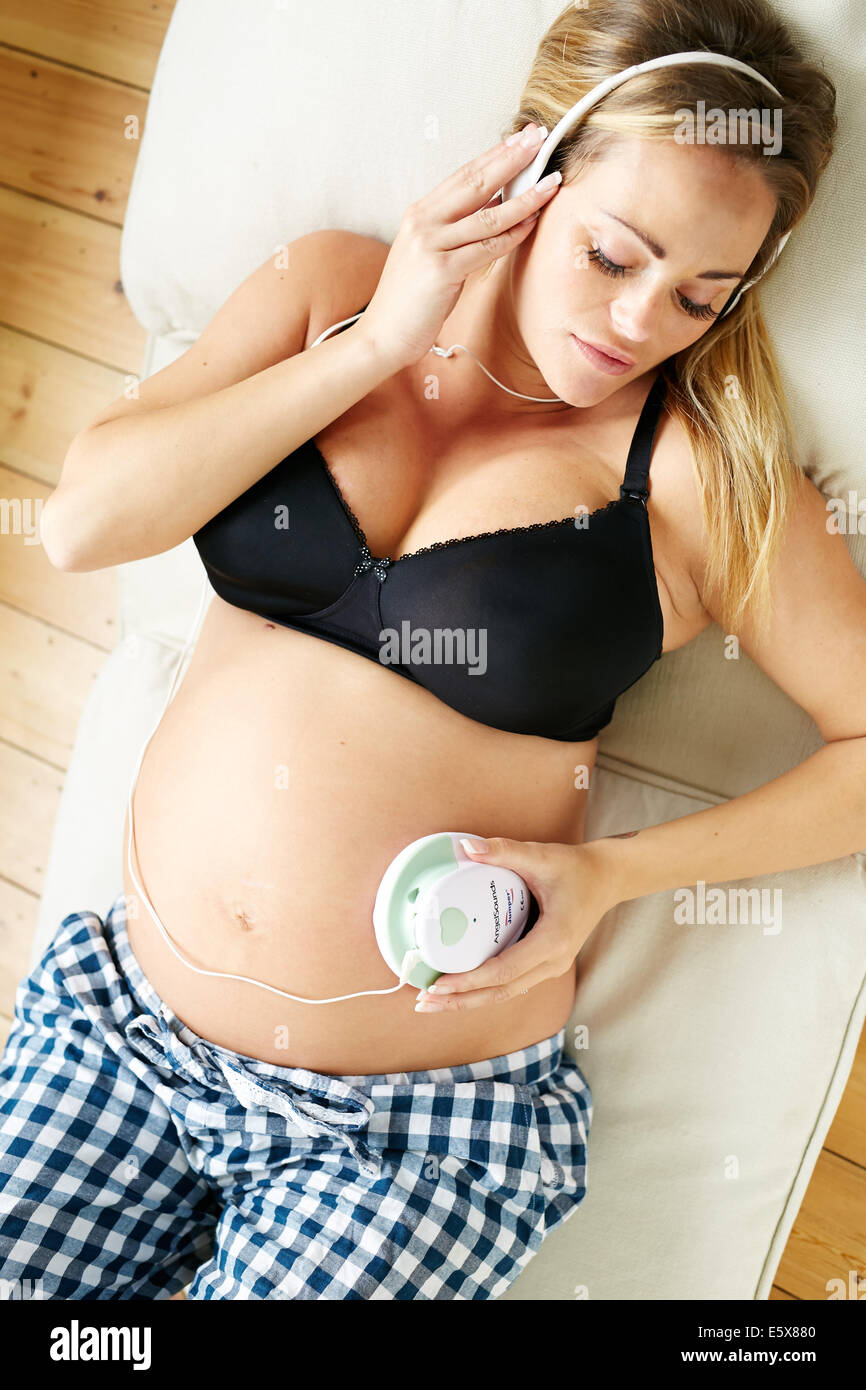 Future Mom holding headphones on her big belly, while her unborn baby  listening pleasant sounds and melody. First Child Anticipation Stock Photo  - Alamy