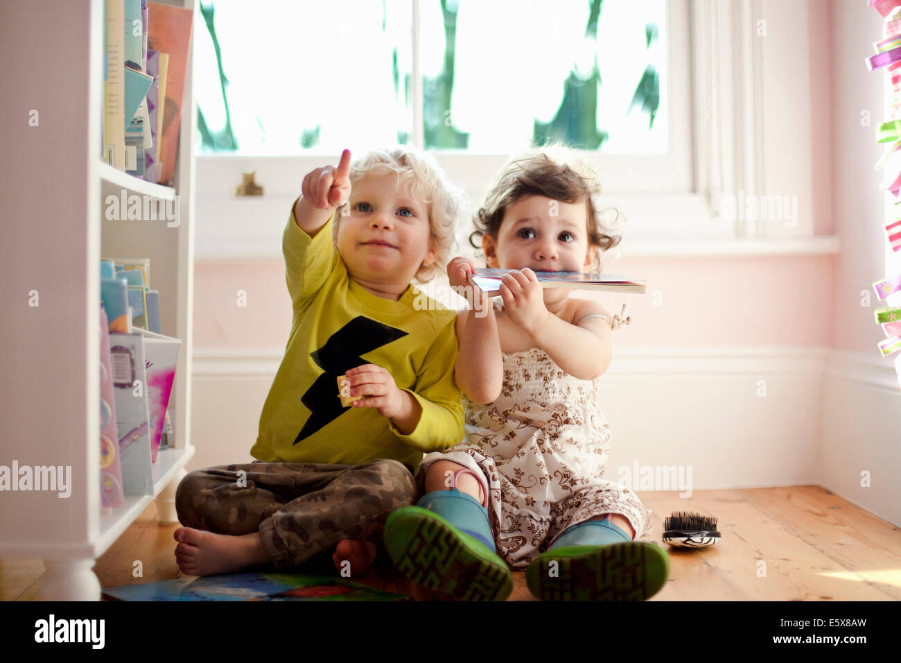 Female and male toddler friends pointing and looking up Stock Photo