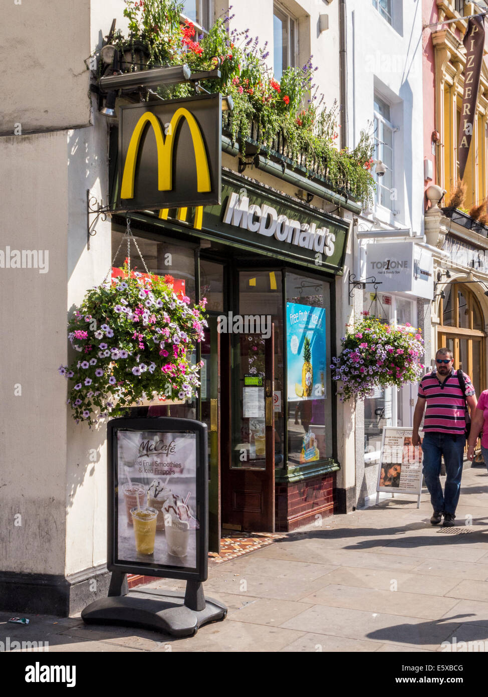 McDonald's fast food outlet and McCafe with gold M Logo and flower baskets in Summer - Richmond upon Thames, Surrey,London Stock Photo