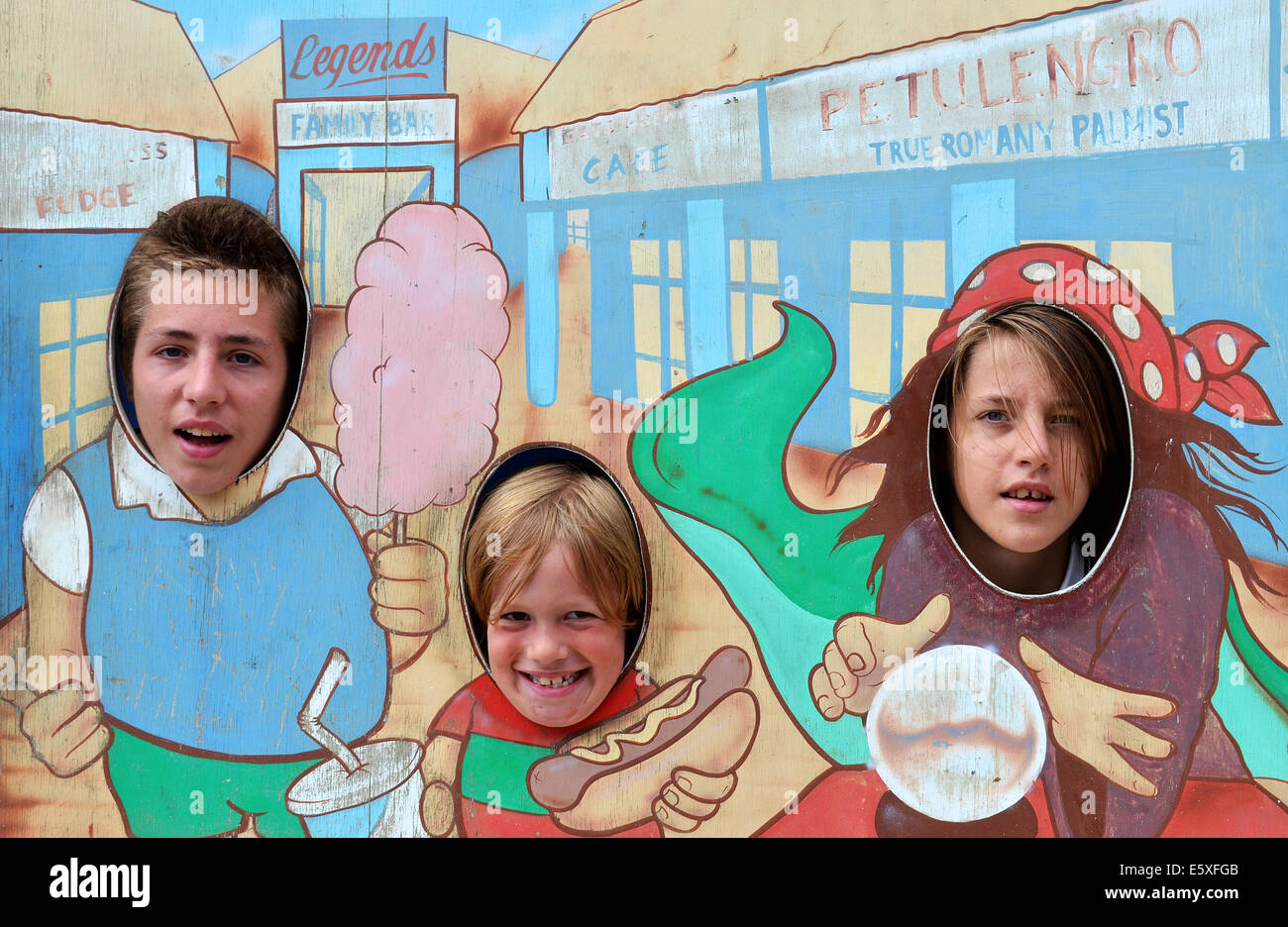 Three children have the photo taken at a fairground peep through board on the pier at blackpool, england, uk Stock Photo