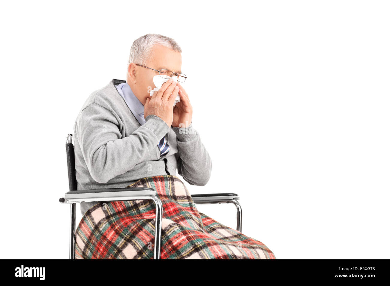 Senior man in wheelchair blowing his nose in a tissue Stock Photo
