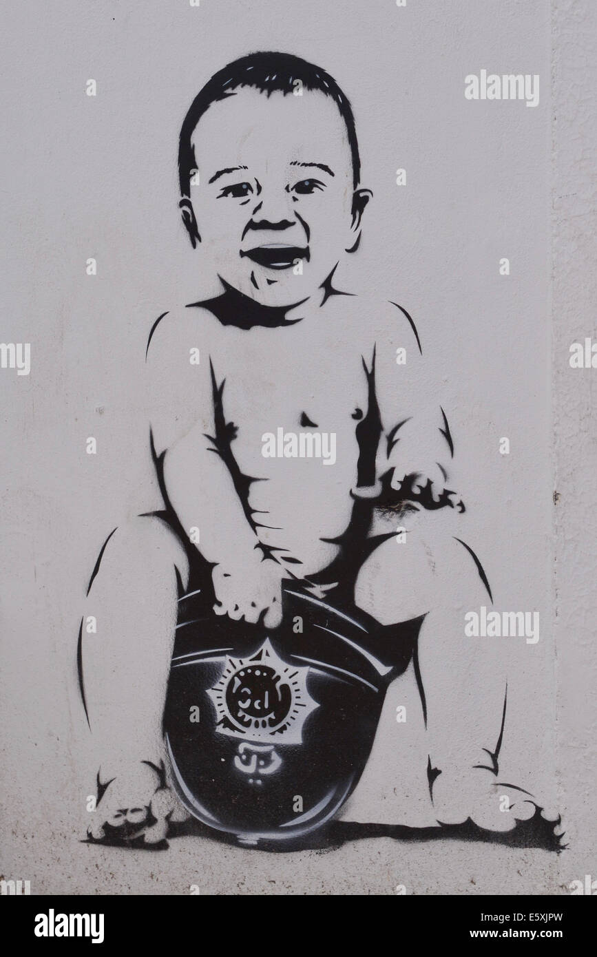 Grafitti stencil, baby sitting pooing inside policeman's hat Stock Photo
