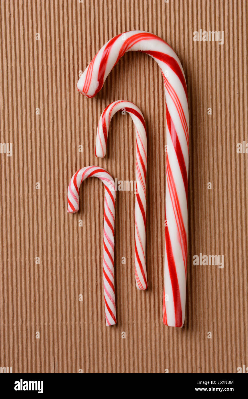 Three different Christmas candy canes on a corrugated cardboard surface