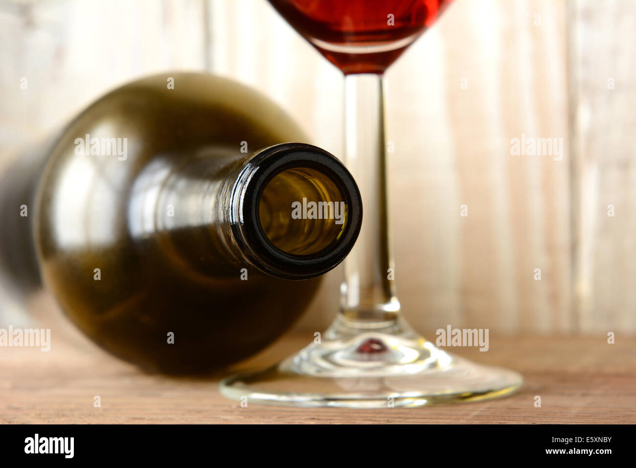 Wine still life with a bottle on its side and the bottom of a glass of red wine on a wood background. Horizontal format. Stock Photo