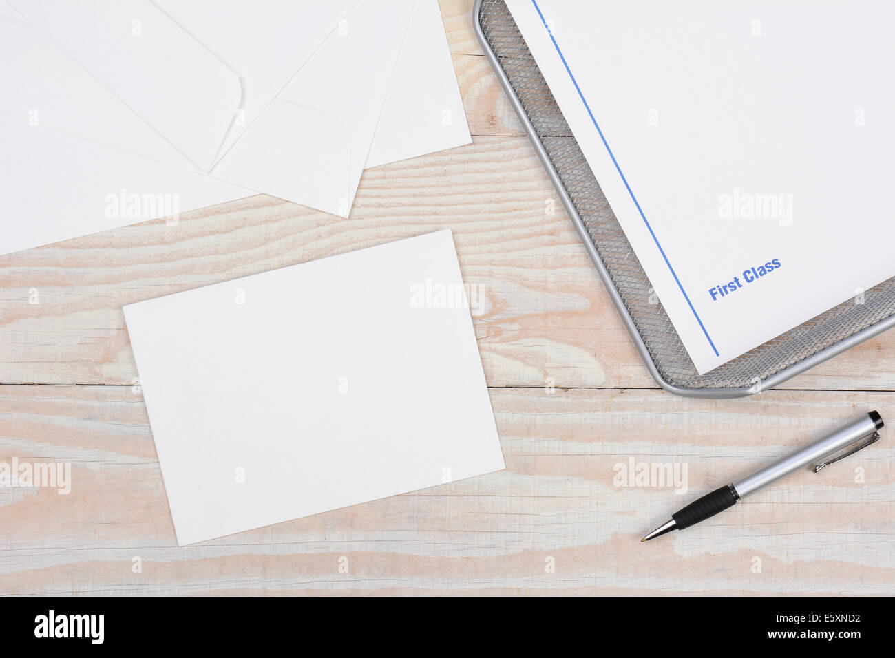 Envelopes and paper for writing letters via snail mail. High angle shot with in-box and pen on a whitewashed desk. Stock Photo