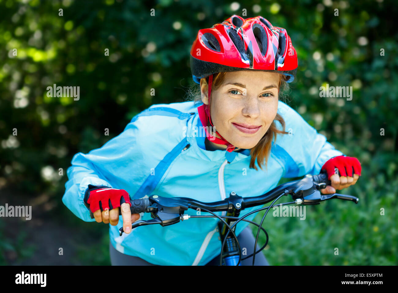 Happy Young woman leaned over the handlebars of her bike. Stock Photo