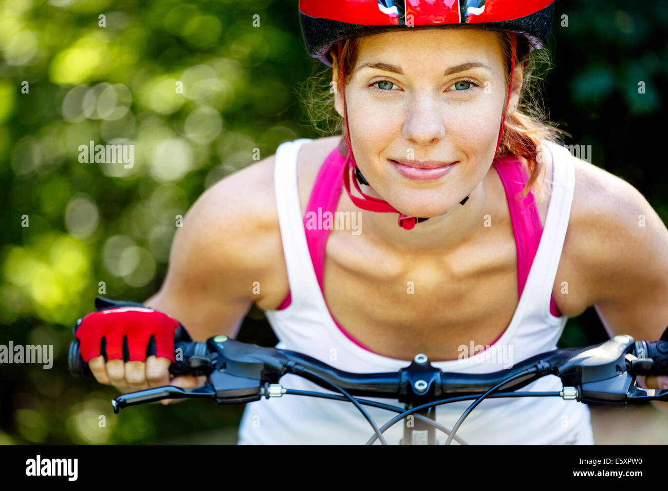 Happy Young woman leaned over the handlebars of her bike. Stock Photo