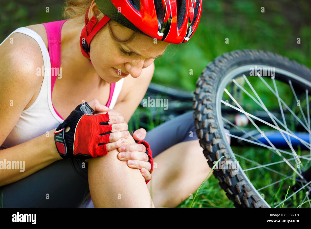 Young woman fell off mountain bike. Stock Photo