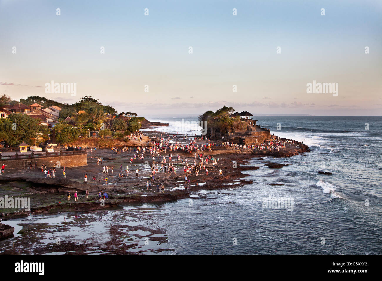 Tourists flock to the sacred pilgrimage temple of Tanah Lot in Bali. A travel destination and famous place popularized by the rock temple in the sea Stock Photo