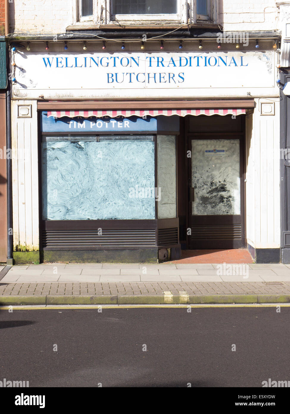 Traditional high street business butchers shop closed down with whitewashed window. Stock Photo