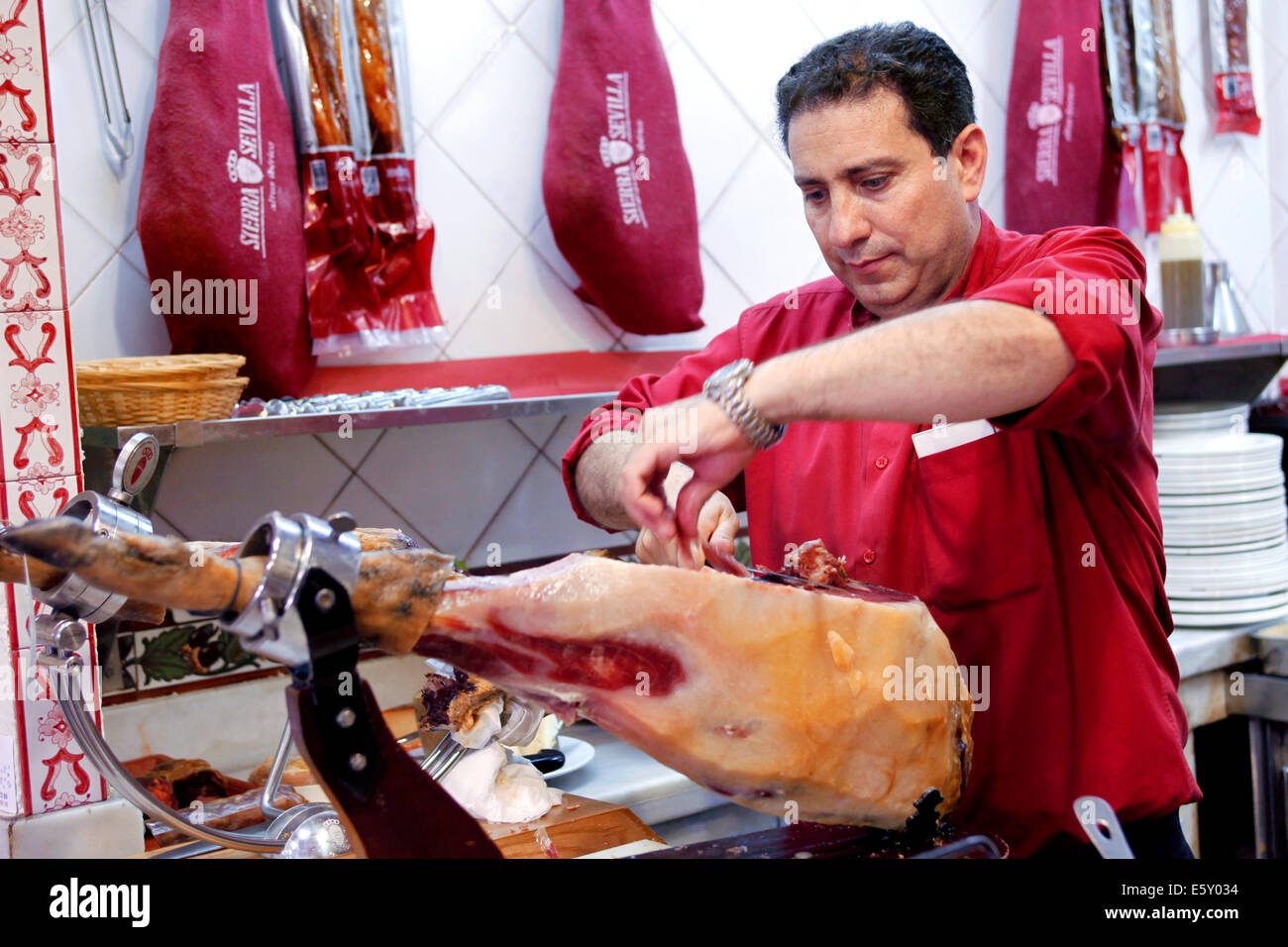 Waiter carving / cutting  / slicing a leg of Jamón Serrano / Jamon Bellota cured ham with a knife, Mesón Sierra de Sevilla Restaurant, Seville, Spain Stock Photo