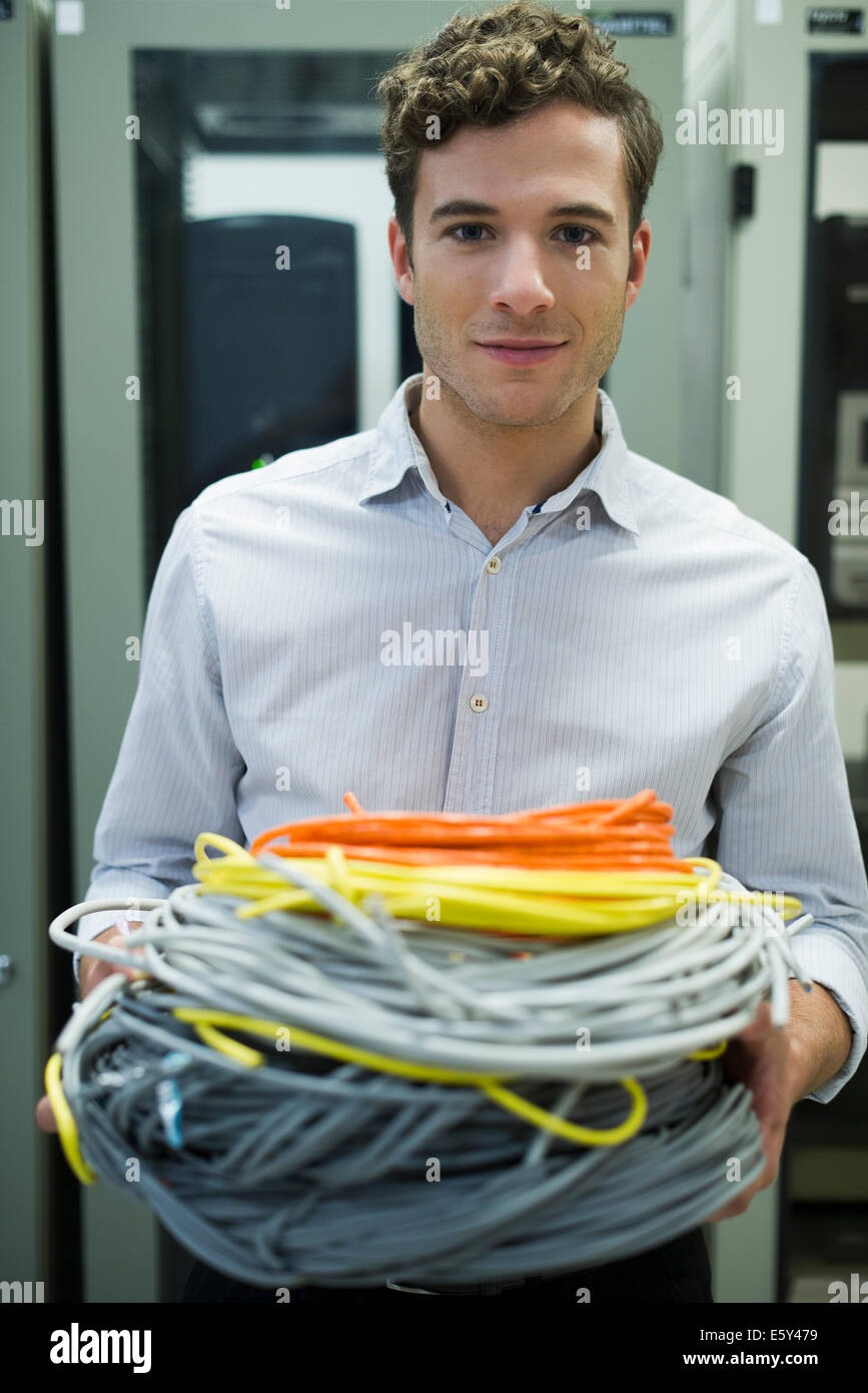Computer technician carrying coils of networking cables into server room Stock Photo
