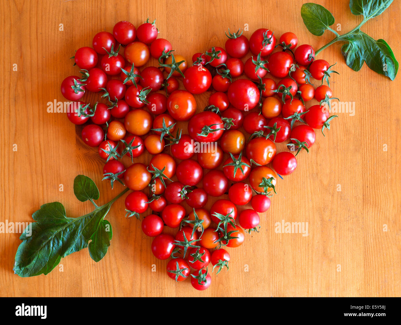 Cherry tomatoes in heart shape with arrow made from leaf Stock Photo