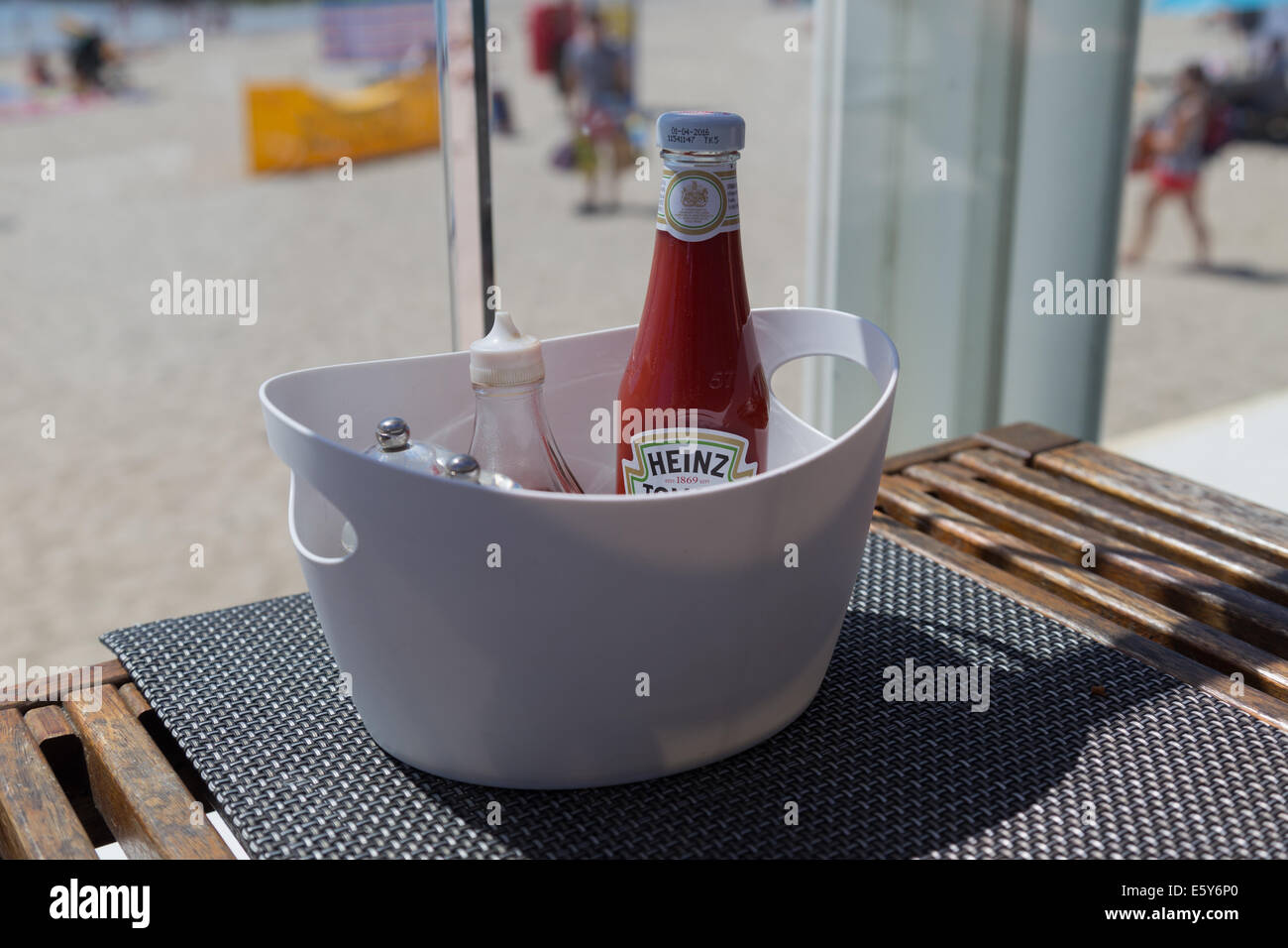 Tomato sauce/ ketchen and other condiments on a wooden beach site table Stock Photo