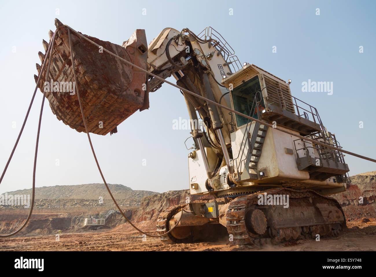 An electric Liebherr face shovel operator lifts its own power cable whilst relocating in an African copper mine. Stock Photo