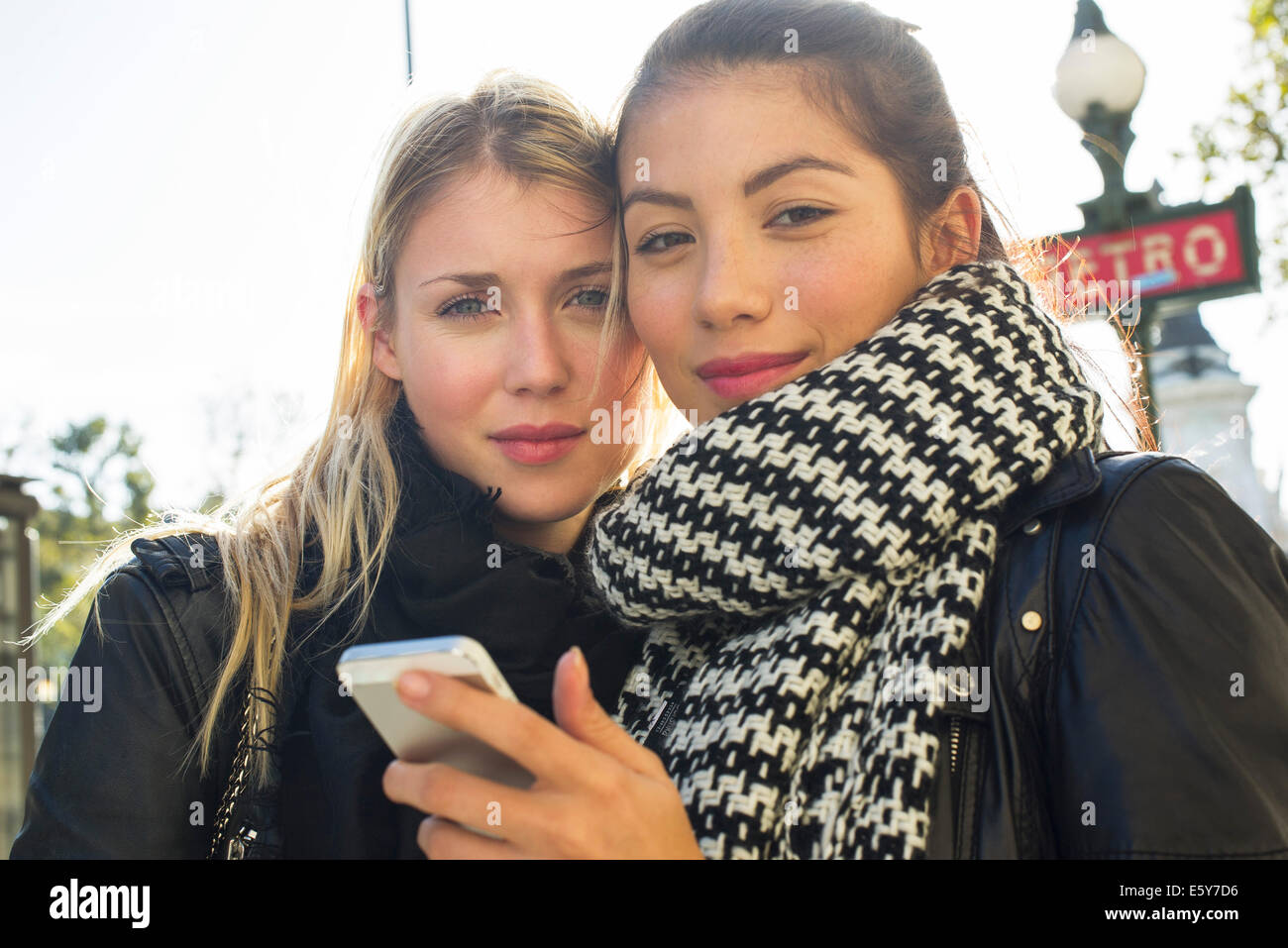 Young women outdoors looking at cell phone together Stock Photo