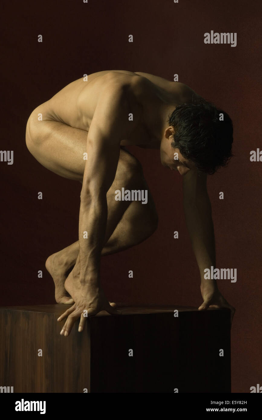 Nude man crouching, head down Stock Photo