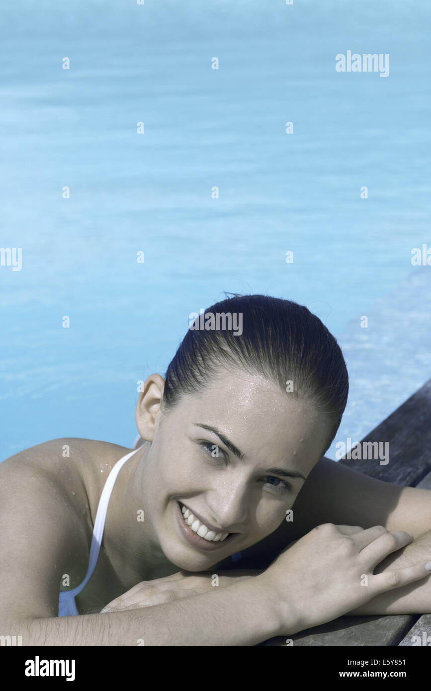 Young woman leaning on poolside, smiling Stock Photo