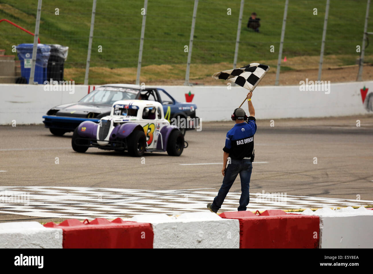 A Race Official Waves The Chequered Flag During Racing At Auto Clearing Motor Speedway A Race Official Waves The Chequered Flag During Racing At Auto Clearing Motor Speedway