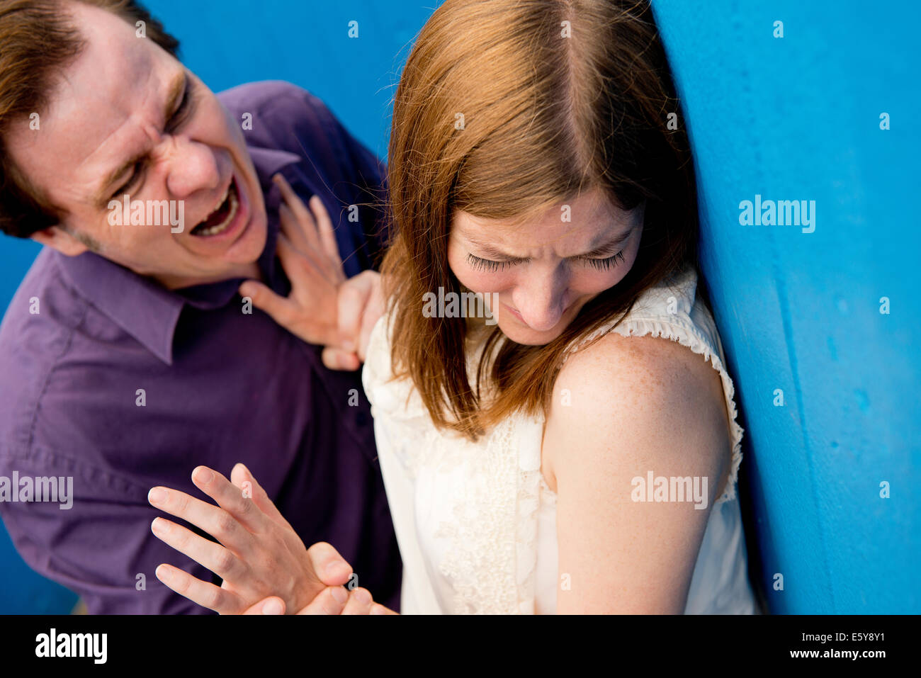 Aggressive man displaying violent behaviour and verbal abuse towards a helpless woman. Stock Photo