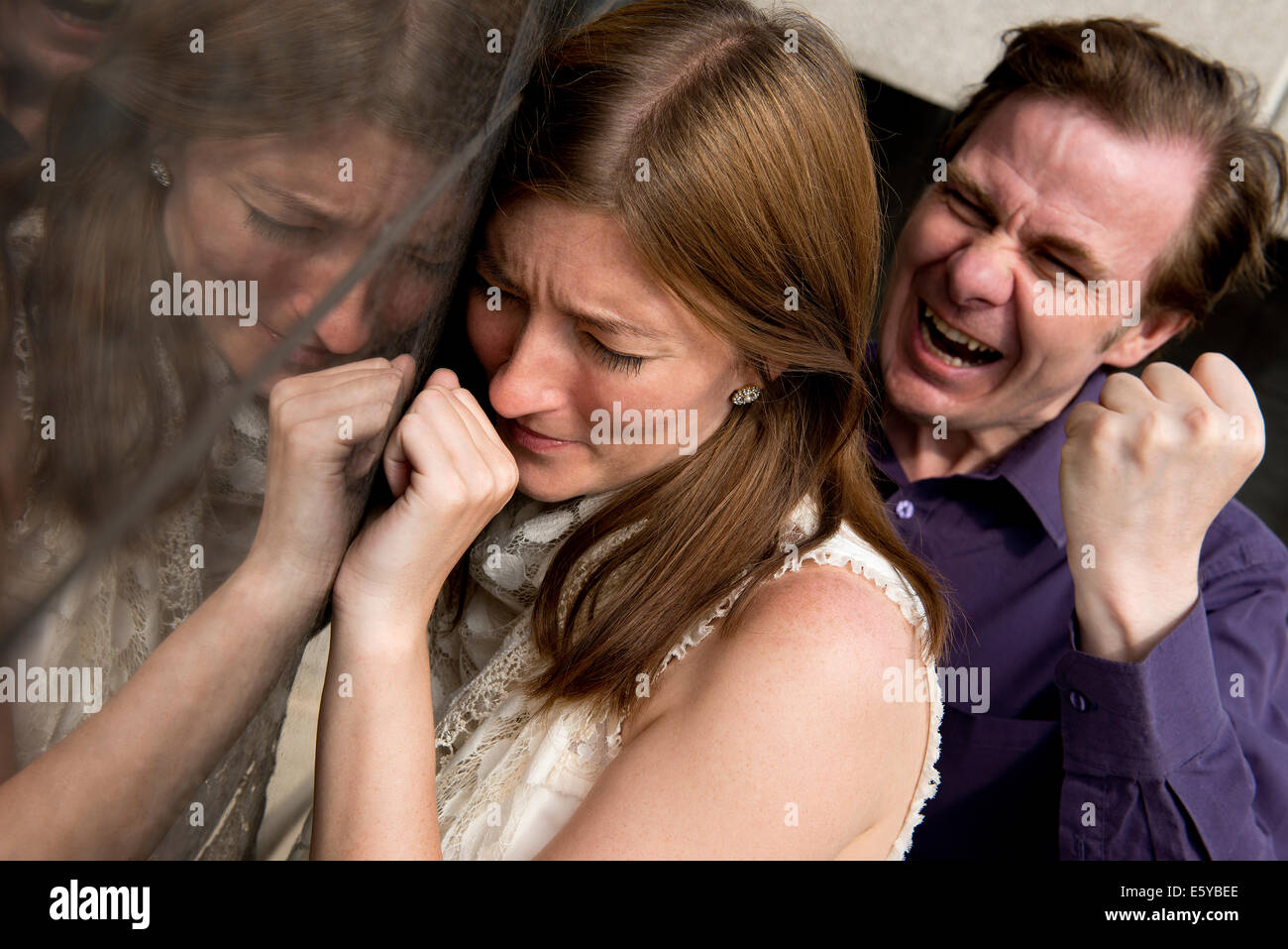 Aggressive man lashing out on a frightened woman with tirade of verbal abuse and threatening behaviour. Stock Photo