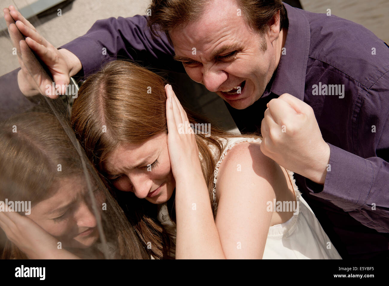 Aggressive man lashing out on a frightened woman with tirade of verbal abuse and threatening behaviour. Stock Photo
