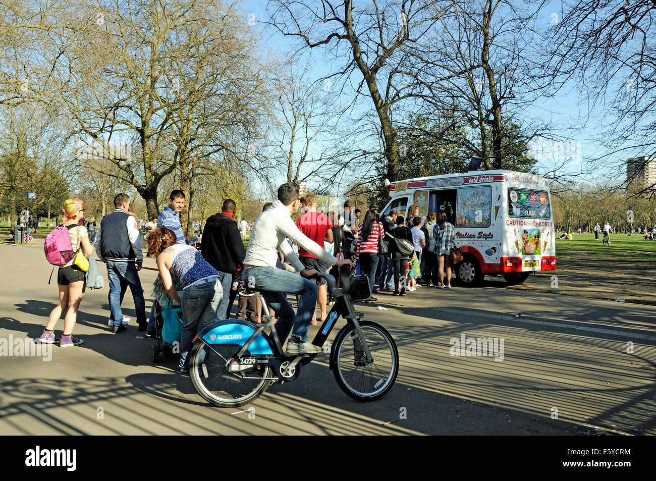 Queue at ice cream van with passing cyclist on Barclays bike, Victoria Park, London Borough of Tower Hamlets, England Britain UK Stock Photo