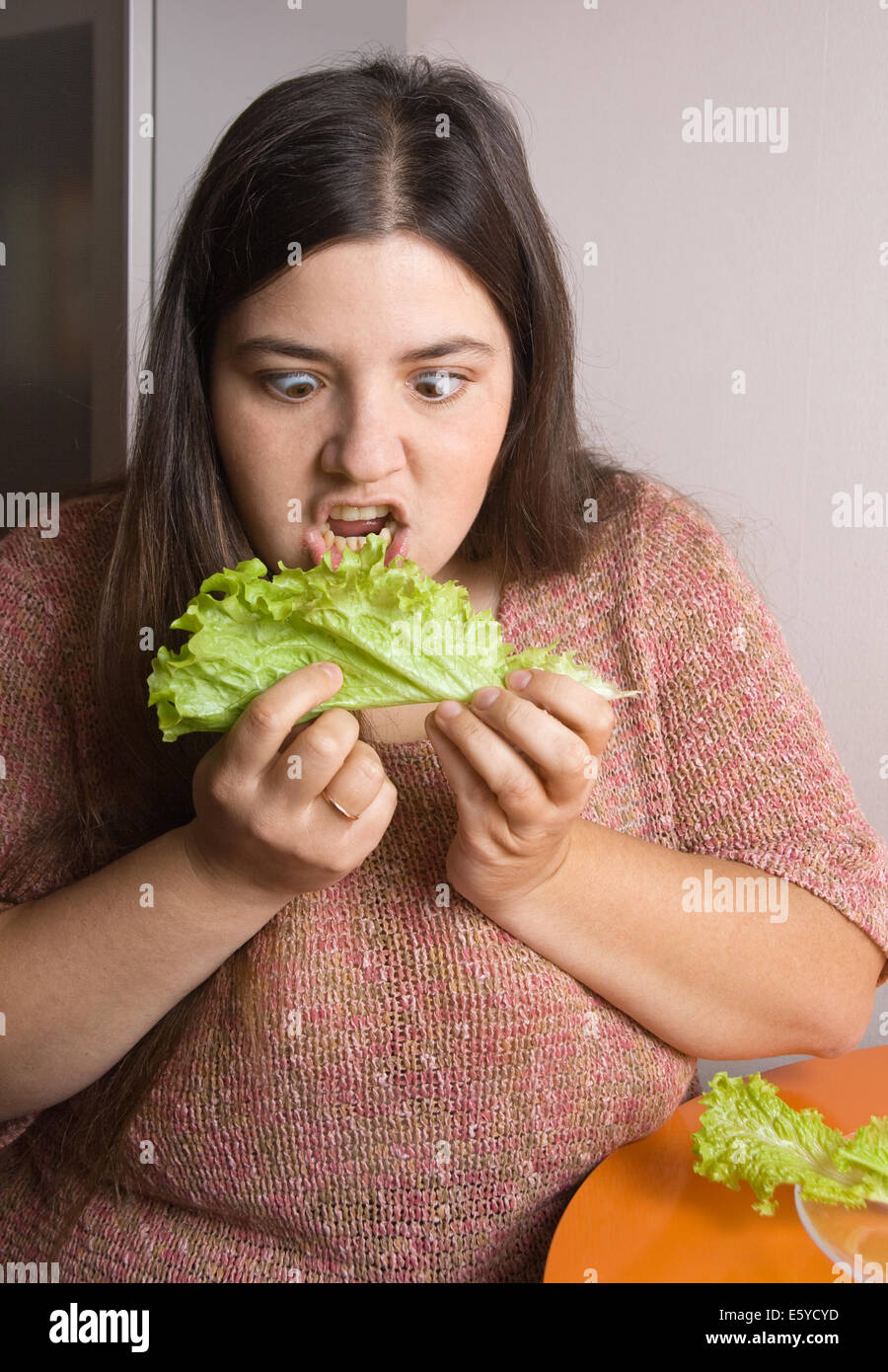 Stout woman trying to eat a leaf of lettuce Stock Photo Alamy