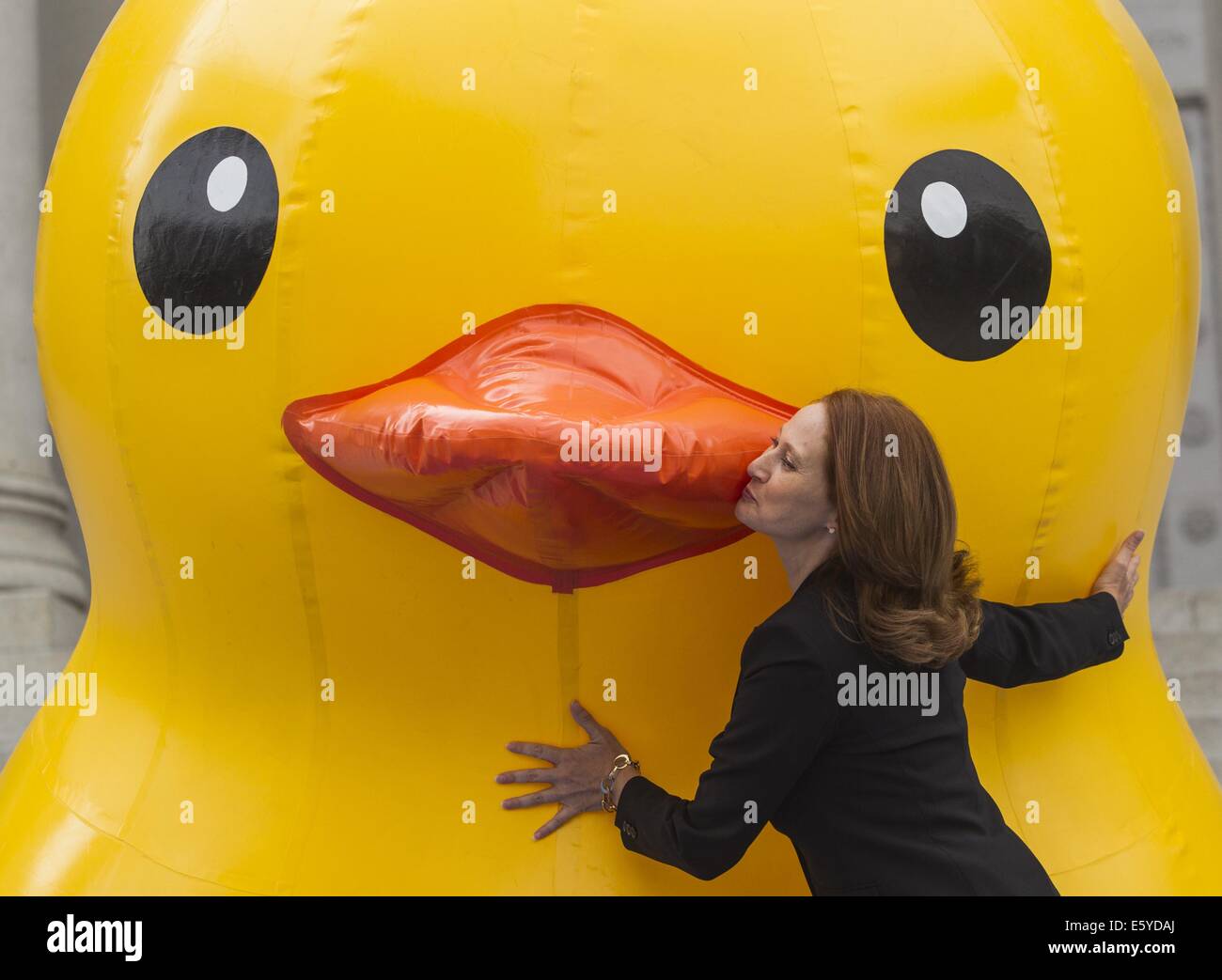 Los Angeles, California, USA. 8th Aug, 2014. Amy Wakeland, wife of Los Angeles Mayor Eric Garcettia, poses with a 10-foot-tall rubber ducky ''baby duck'' squatting on the Spring Street steps of Los Angeles City Hall on Friday, Aug. 8, 2014, in Los Angeles. The bright yellow, inflatable ducky is wandering the city in search of its mother, a 60 feet high and dubbed by event organizers as the world's largest rubber ducky as part of a promotional stunt for the Tall Ships Festival taking place Aug. 20-24 at the Port of Los Angeles. Credit:  Ringo Chiu/ZUMA Wire/Alamy Live News Stock Photo