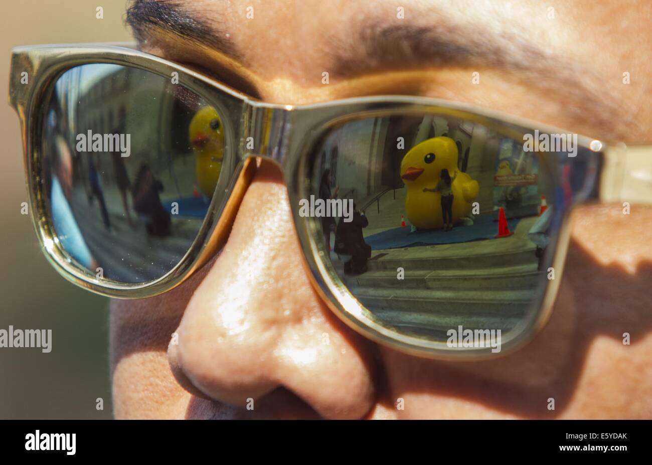 Los Angeles, California, USA. 8th Aug, 2014. People take pictures with a 10-foot-tall rubber ducky ''baby duck'' are reflected on a glasses, on the Spring Street steps of Los Angeles City Hall on Friday, Aug. 8, 2014, in Los Angeles. The bright yellow, inflatable ducky is wandering the city in search of its mother, a 60 feet high and dubbed by event organizers as the world's largest rubber ducky as part of a promotional stunt for the Tall Ships Festival taking place Aug. 20-24 at the Port of Los Angeles. Credit:  Ringo Chiu/ZUMA Wire/Alamy Live News Stock Photo
