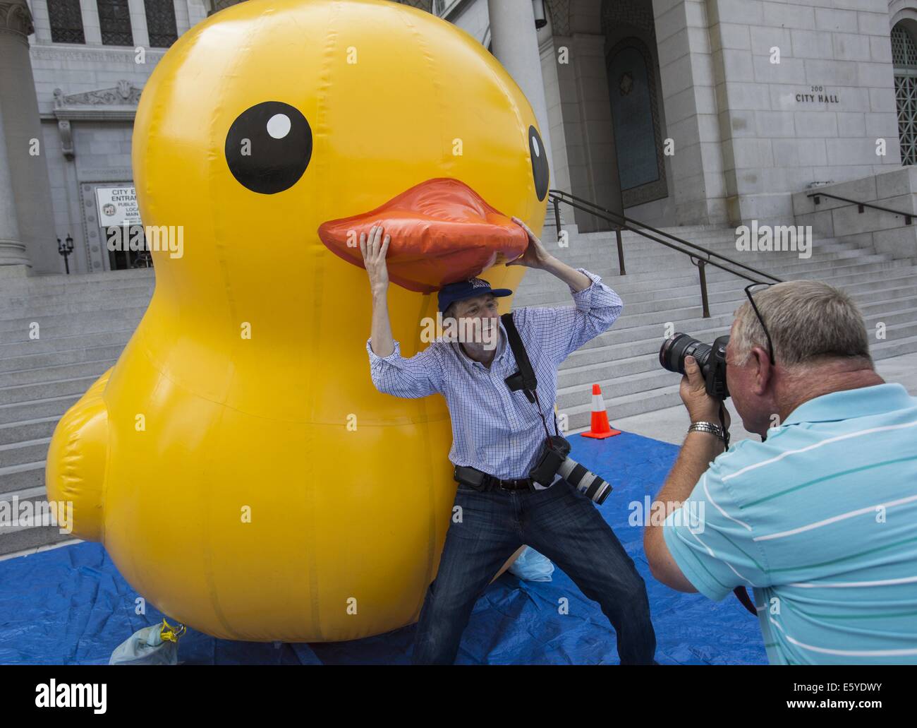 Los Angeles, California, USA. 8th Aug, 2014. Los Angeles Times photographer Gary Friedman poses with a 10-foot-tall rubber ducky ''baby duck'' squatting on the Spring Street steps of Los Angeles City Hall on Friday, Aug. 8, 2014, in Los Angeles. The bright yellow, inflatable ducky is wandering the city in search of its mother, a 60 feet high and dubbed by event organizers as the world's largest rubber ducky as part of a promotional stunt for the Tall Ships Festival taking place Aug. 20-24 at the Port of Los Angeles. Credit:  Ringo Chiu/ZUMA Wire/Alamy Live News Stock Photo