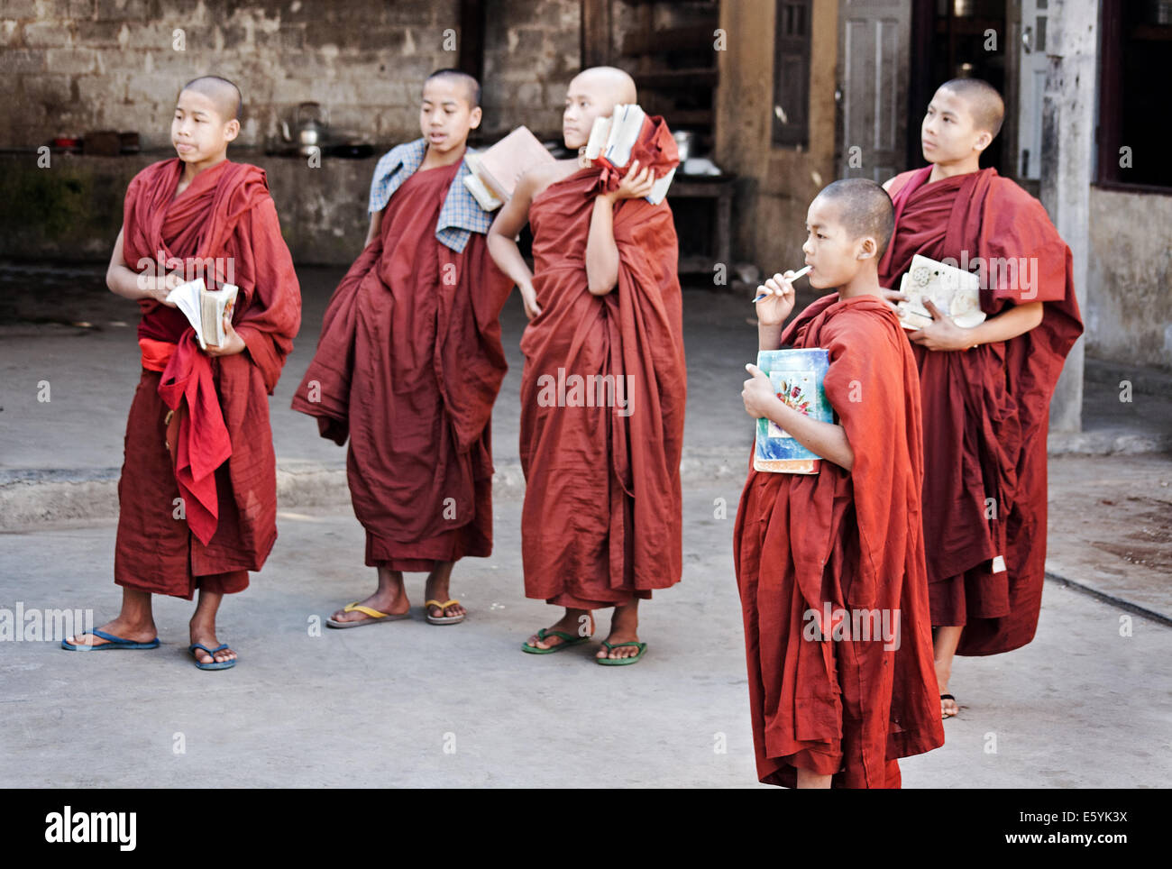 Novice Burmese Buddhist monks listening to a discourse with learning materials at the ready in a Buddhist monastery dressed in traditional robes Stock Photo