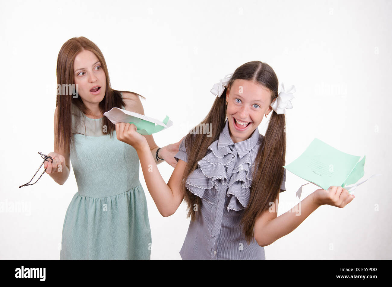Schoolgirl having fun tearing the notebook in front of an angry teacher Stock Photo