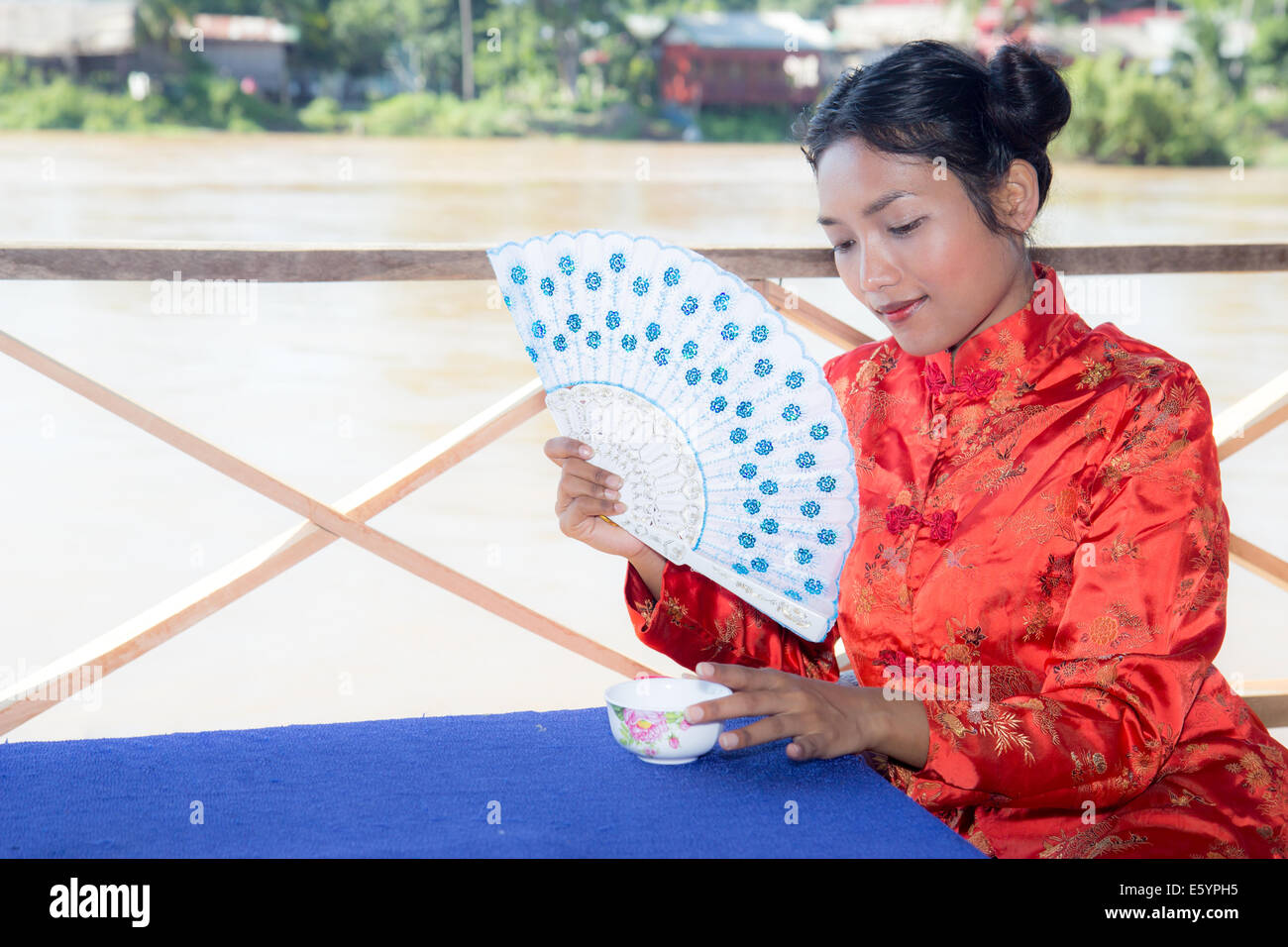 Asian woman holding fan and cup Stock Photo
