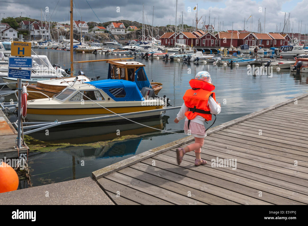 Little girl dressed in a life jacket,  in the port of Skärhamn, Bohuslän, Västra Götaland Iän, Sweden. Stock Photo