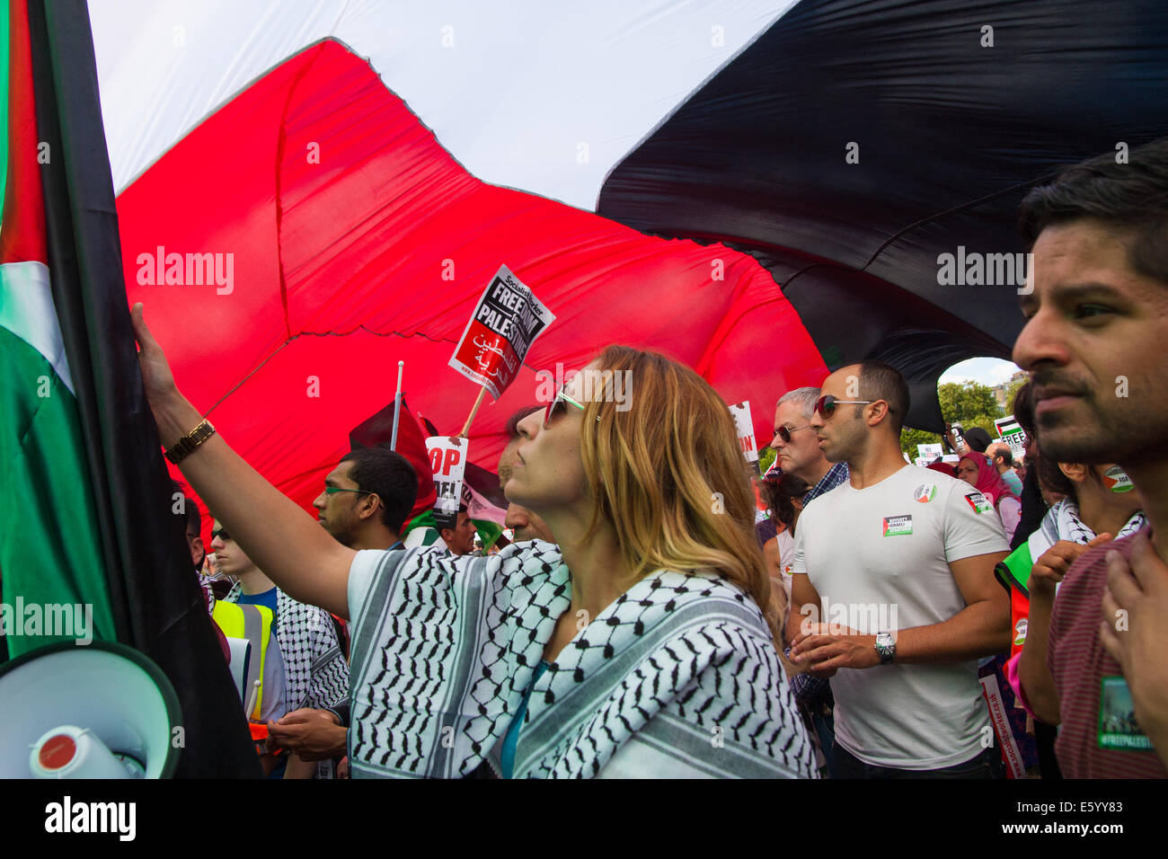 London, UK. 9th August, 2014.  Protesters listen to speeches under a giant Palestinian flag as tens of thousands attend a rally in support of the people of Palestine. Credit:  Paul Davey/Alamy Live News Stock Photo