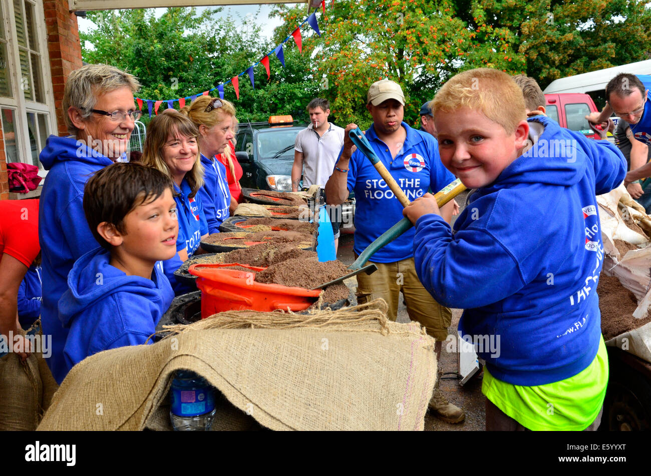 Burrowbridge, Somerset, UK. 9th August, 2014. UK weather:  An Emergency call out for local helpers to make more Sandbags to be put in place around the bridge and along the Main Road opposite due to very bad weather forecast moving in.Picture shows young helpers L/R. Steh and Ryan. Stock Photo