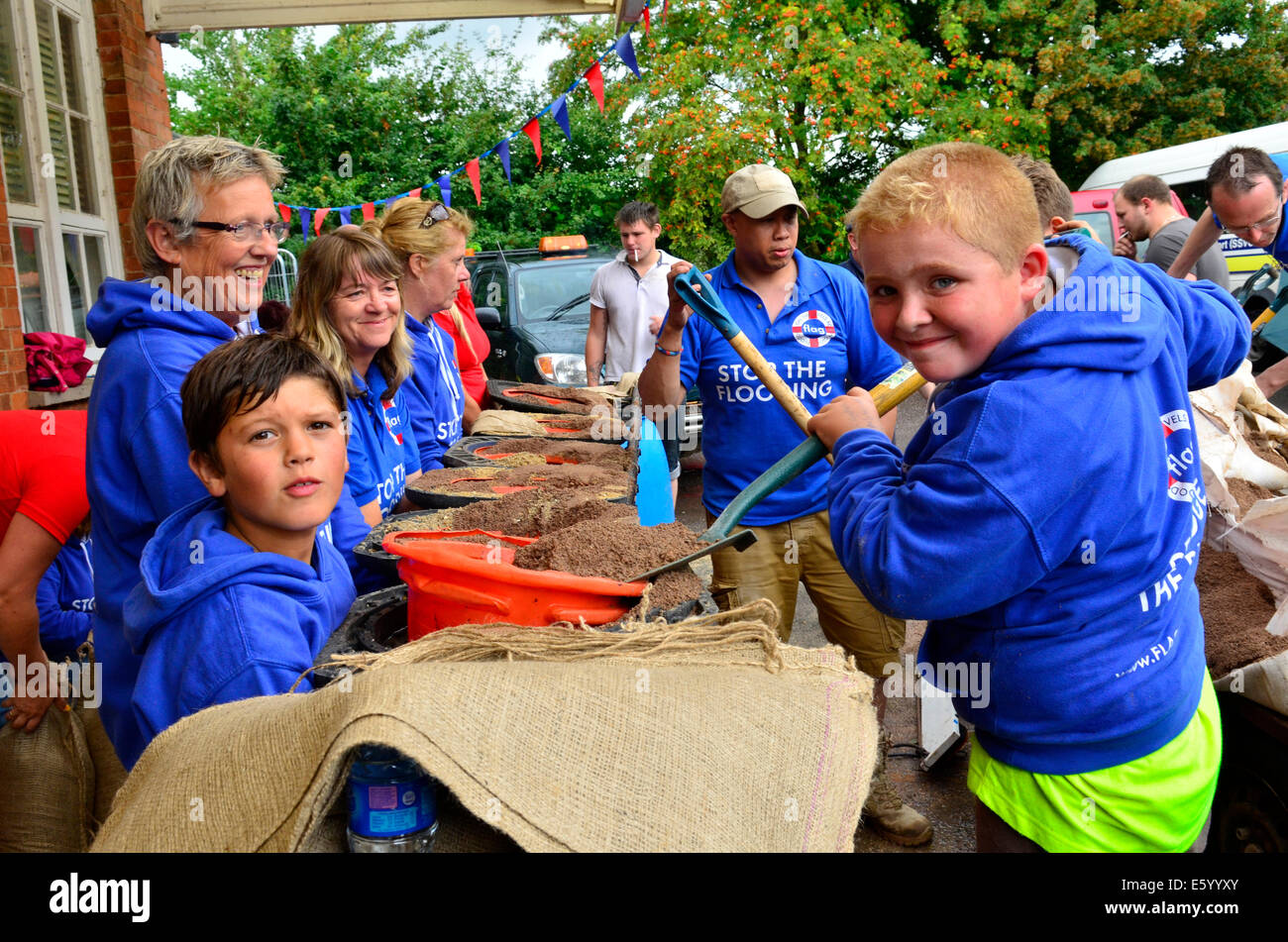 Burrowbridge, Somerset, UK. 9th August, 2014. UK weather: An Emergency call out for local helpers to make more sandbags to be put in place around the bridge and along the Main Road opposite due to very bad weather forecast Moving in Picture Shows, Seth left and Ryan right Helping. Credit: Robert Timoney/Alamy Live News Stock Photo