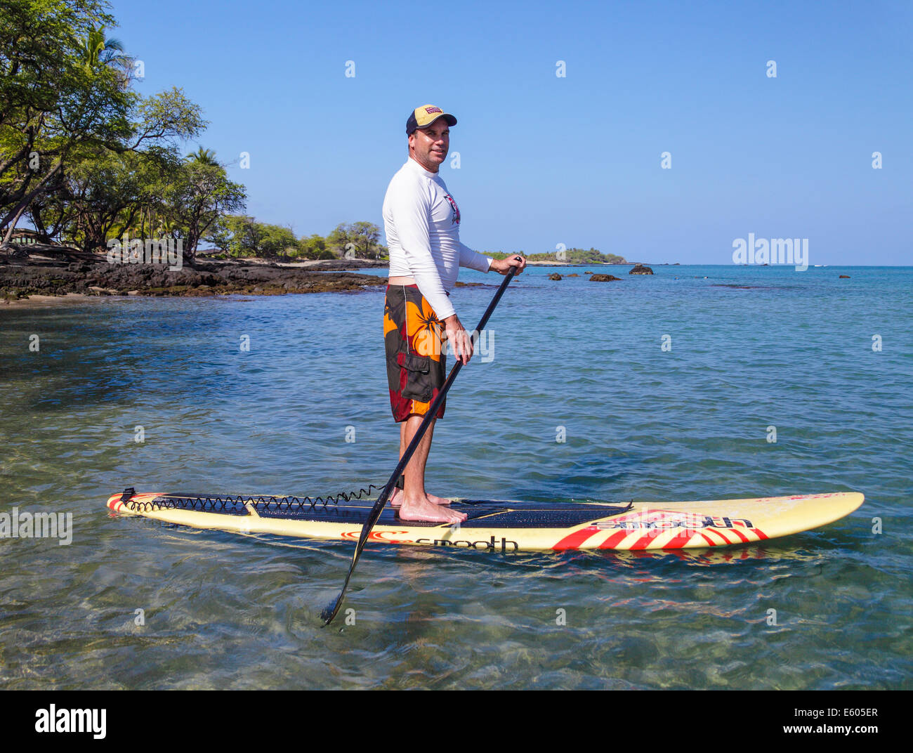 Man stand up paddling in Anaehoomalu Bay on the Big Island of Hawaii Stock Photo