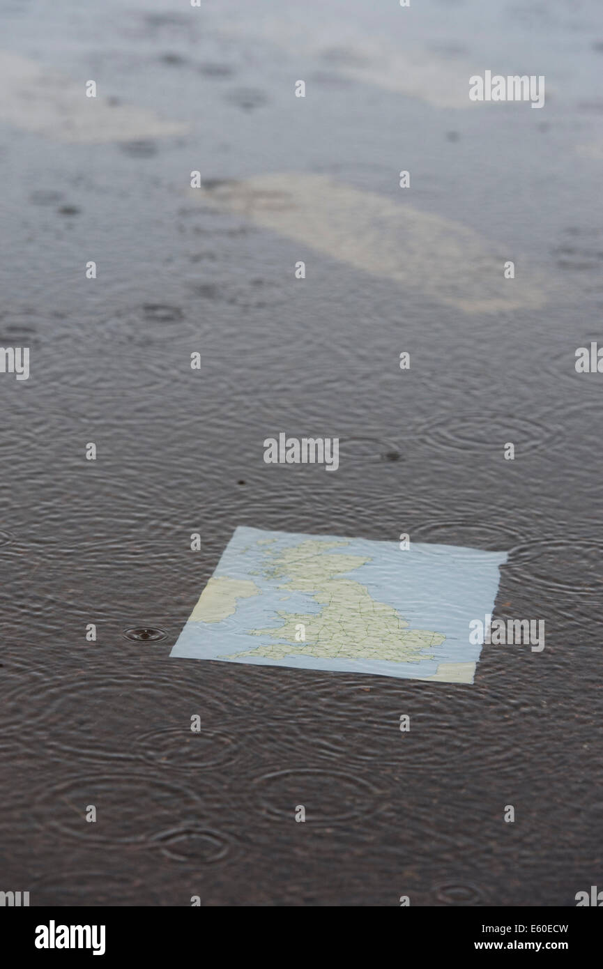 Map of The United Kingdom in a puddle on a road in the rain. Stock Photo