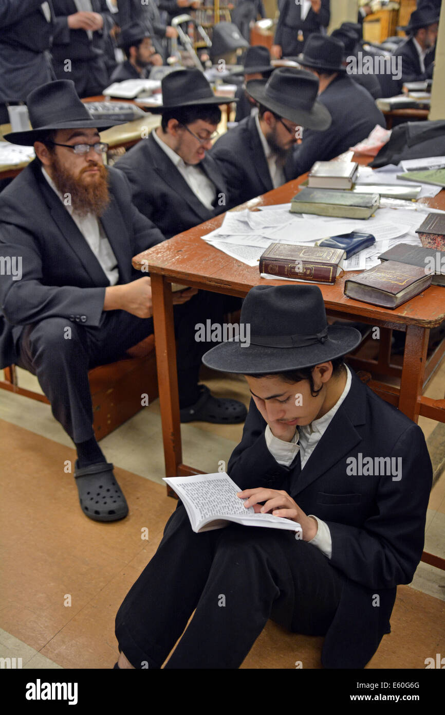 Young religious Jewish men praying during Tisha B'Av services in a synagogue in Brooklyn, New York, USA Stock Photo