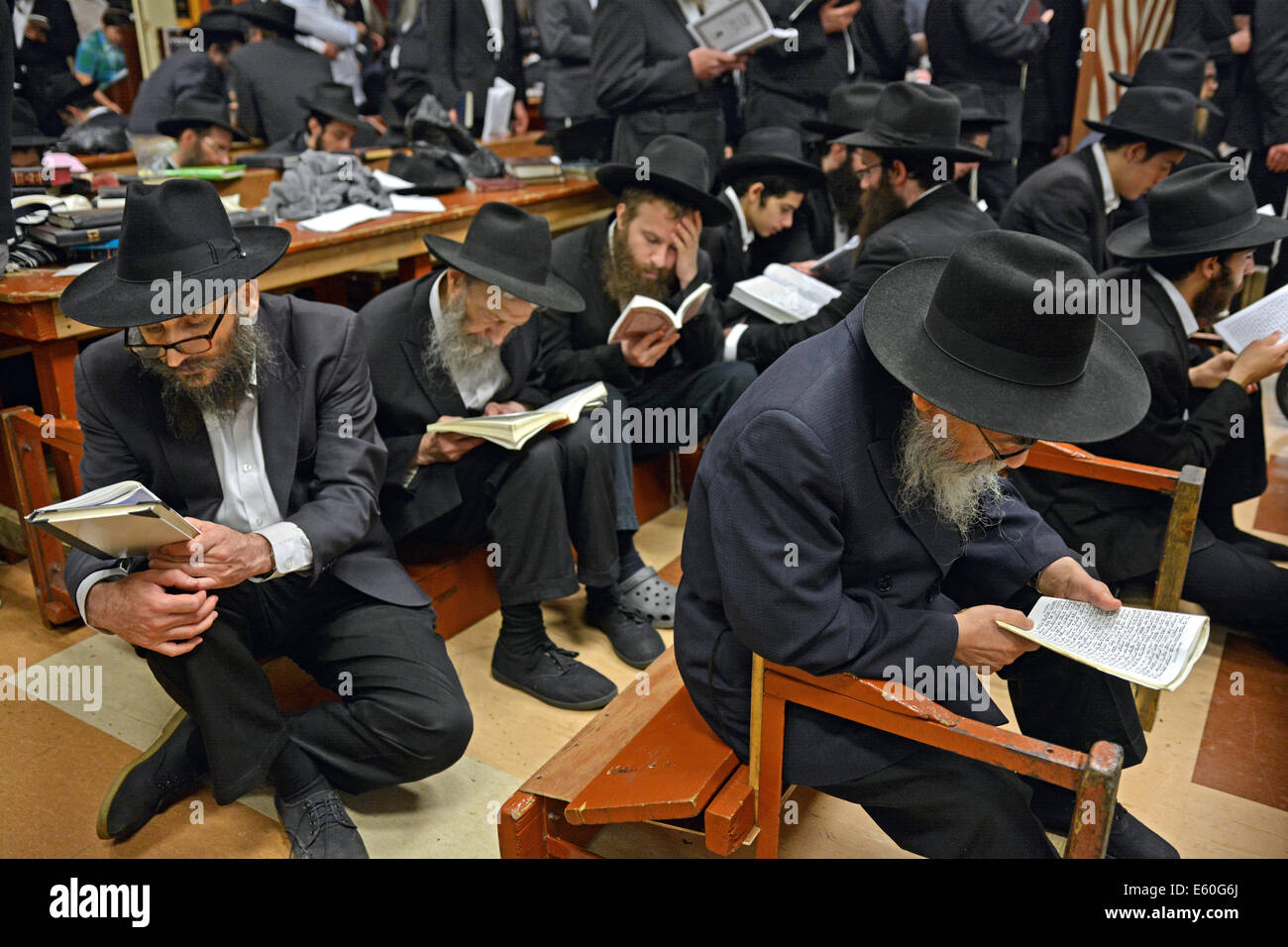 Jewish men praying on Tisha B'Av and following the tradition of sitting in low seats. At a synagogue in Brooklyn, New York. Stock Photo